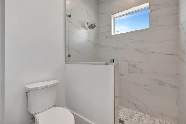 bathroom featuring a marble finish shower and toilet