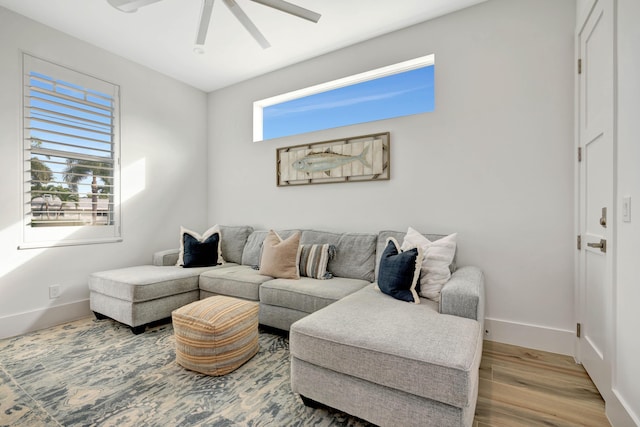living room featuring baseboards, ceiling fan, and wood finished floors