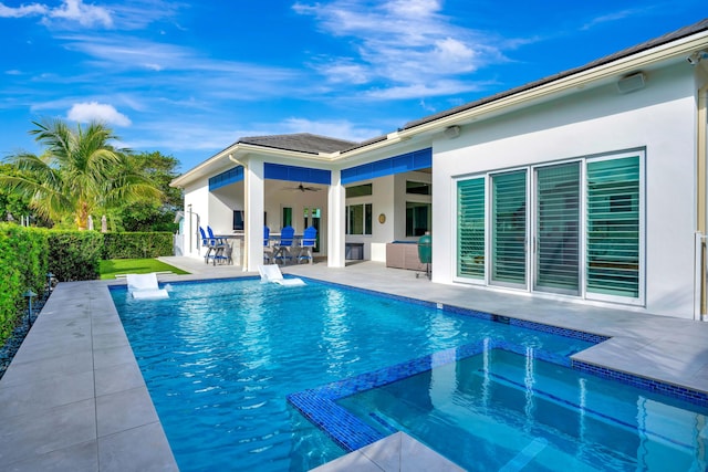 view of swimming pool featuring a ceiling fan, a pool with connected hot tub, a patio area, fence, and outdoor dining space