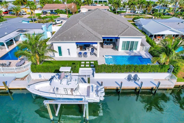 back of property featuring a tiled roof, a water view, a patio area, and boat lift