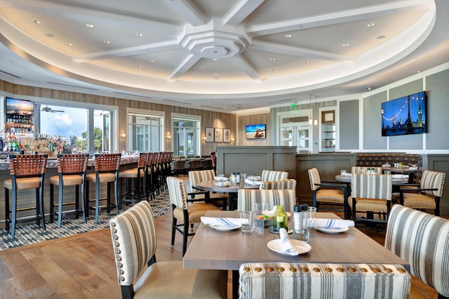 dining space with coffered ceiling, ceiling fan, wood finished floors, and beam ceiling