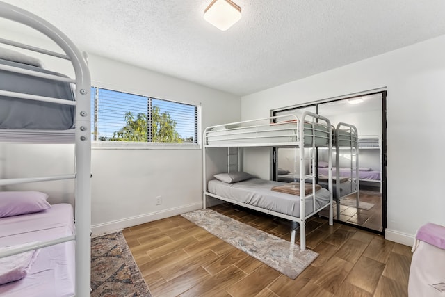 bedroom featuring a textured ceiling, baseboards, and wood finished floors