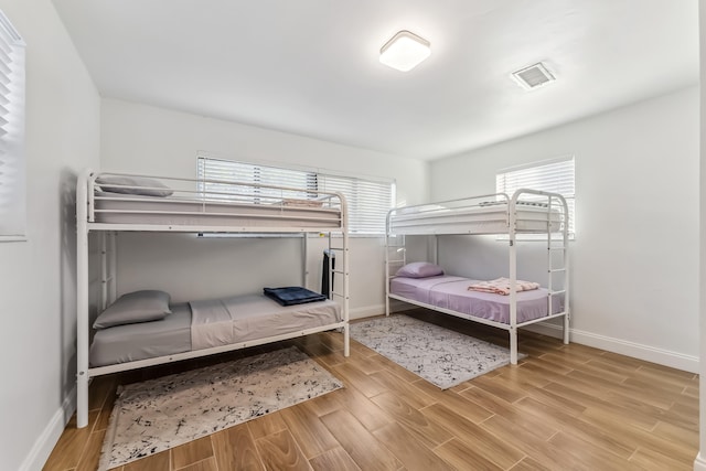 bedroom with baseboards, light wood-style floors, and visible vents