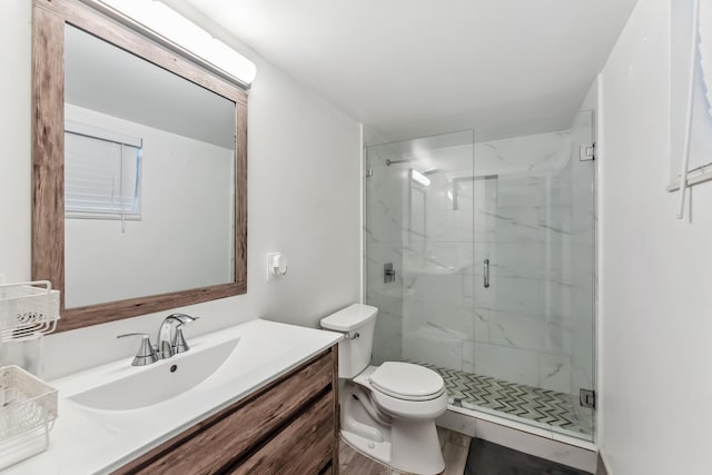 bathroom featuring a marble finish shower, vanity, and toilet