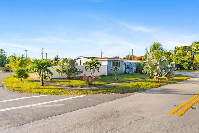 ranch-style house with stucco siding, a front lawn, and fence