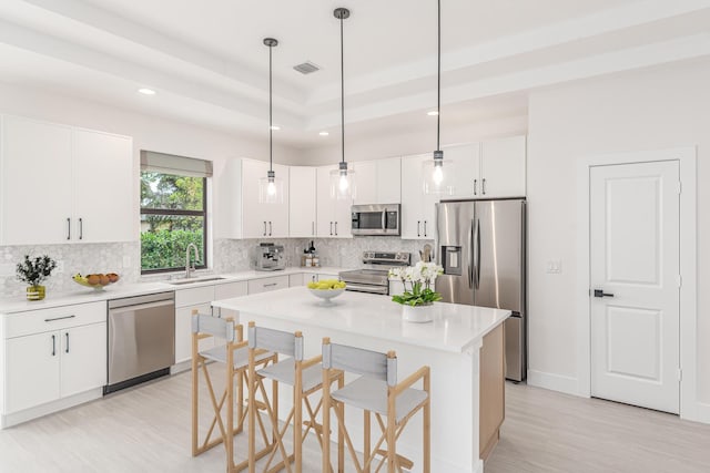 4657 SW Keats St, Port Saint Lucie, FL 34953 - kitchen with appliances with stainless steel finishes, a kitchen breakfast bar, light wood-type flooring, tasteful backsplash, and white cabinets
