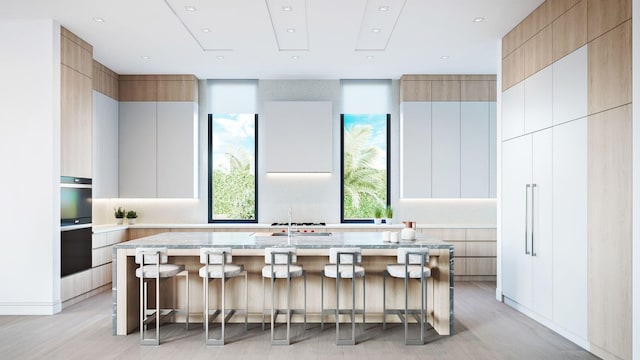 305 Grove Pl, Delray Beach, FL 33444 - kitchen featuring modern cabinets, light wood-type flooring, a breakfast bar, an island with sink, and a sink