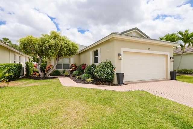 ranch-style home with decorative driveway, an attached garage, a front yard, and stucco siding