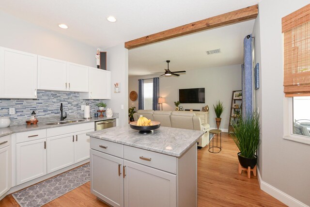 kitchen with backsplash, visible vents, a center island, a sink, and light wood-style flooring