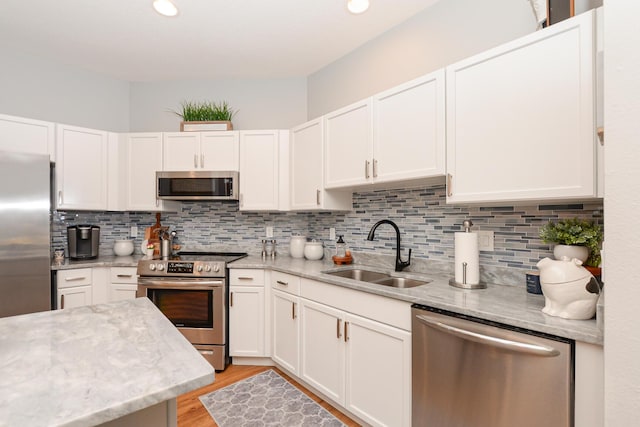 kitchen featuring a sink, appliances with stainless steel finishes, white cabinets, and light wood-style floors