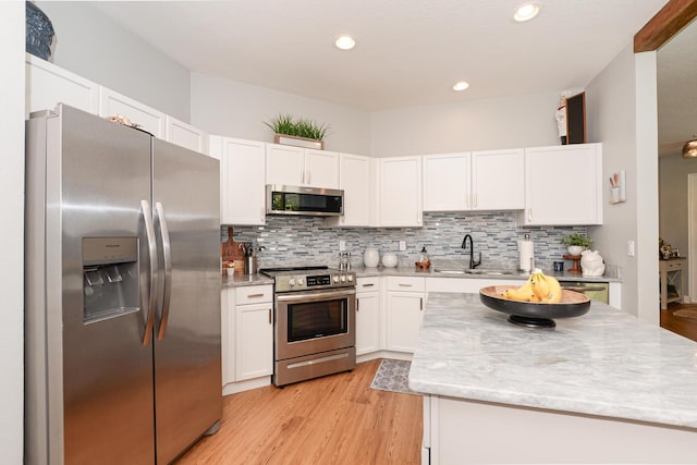 kitchen featuring light wood-type flooring, backsplash, white cabinets, and stainless steel appliances