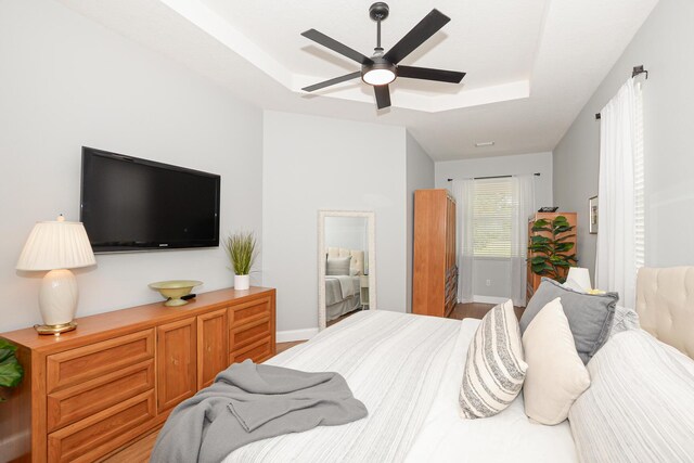 bedroom with ceiling fan, baseboards, and a raised ceiling
