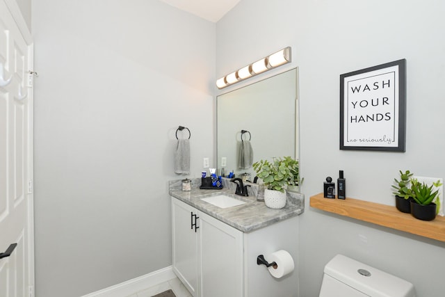 bathroom with vanity, baseboards, and toilet