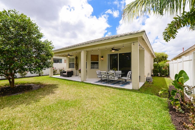 rear view of property featuring stucco siding, a fenced backyard, a lawn, a ceiling fan, and a patio