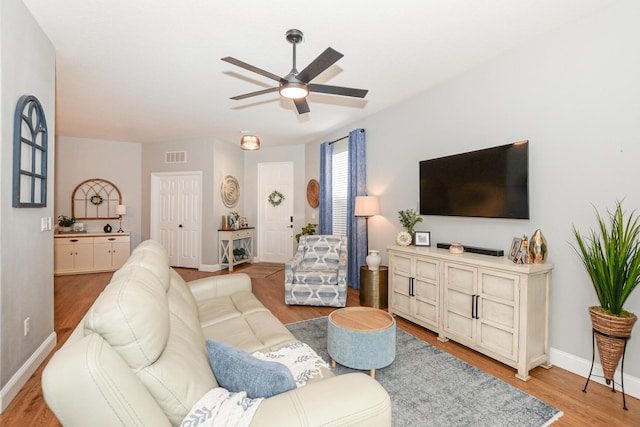 living area featuring baseboards, ceiling fan, wood finished floors, and visible vents