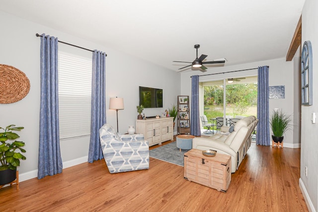 living room featuring baseboards, ceiling fan, and light wood finished floors