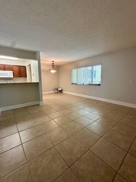 interior space with a textured ceiling, tile patterned floors, and baseboards