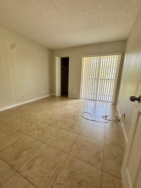 unfurnished room featuring light tile patterned floors, baseboards, and a textured ceiling