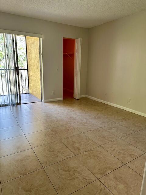 unfurnished room featuring baseboards, a textured ceiling, and light tile patterned floors