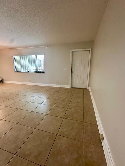 tiled empty room featuring baseboards and a textured ceiling