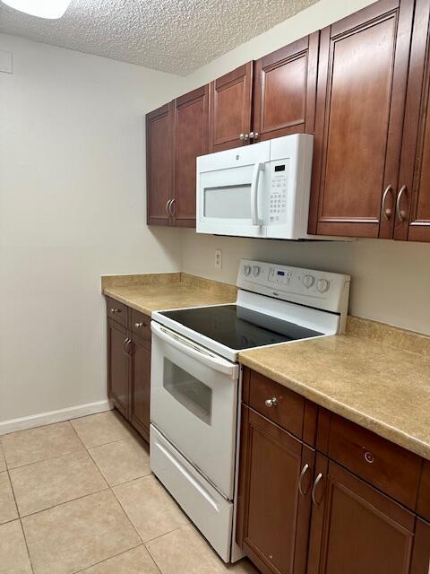 kitchen with white appliances, light tile patterned flooring, baseboards, and light countertops