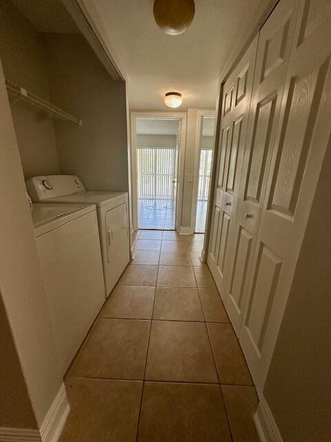 washroom featuring baseboards, laundry area, light tile patterned flooring, and independent washer and dryer