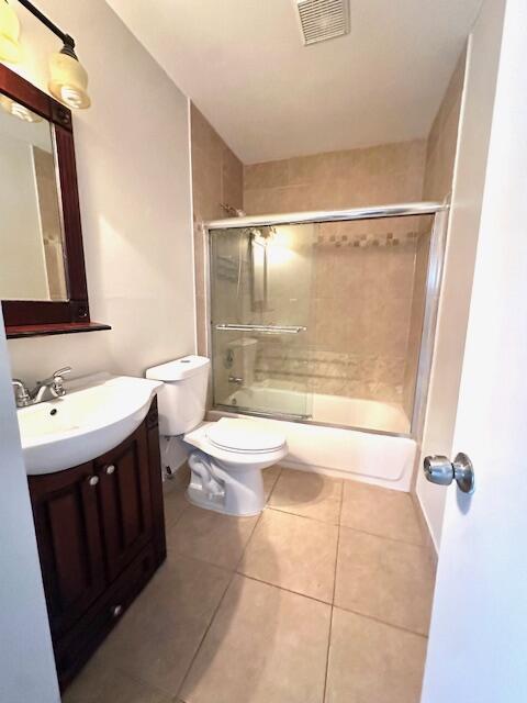full bathroom with visible vents, vanity, shower / bath combination with glass door, toilet, and tile patterned floors