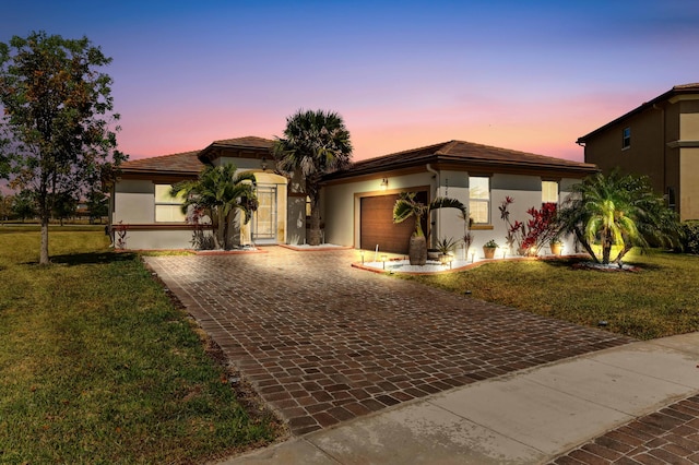 7384 NW Greenspring St, Port Saint Lucie, FL 34987 - view of front of house featuring an attached garage, decorative driveway, stucco siding, and a front lawn