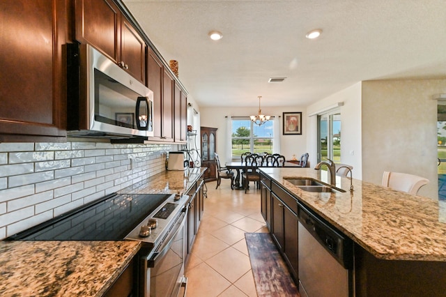 7384 NW Greenspring St, Port Saint Lucie, FL 34987 - kitchen featuring stainless steel appliances, a sink, a chandelier, light stone countertops, and recessed lighting