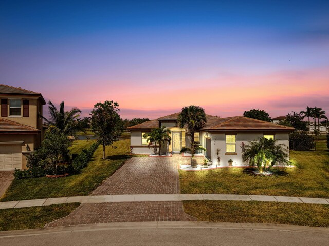 7384 NW Greenspring St, Port Saint Lucie, FL 34987 - mediterranean / spanish-style house featuring decorative driveway, stucco siding, a yard, and a garage