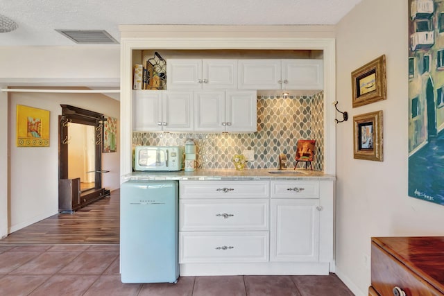 2971 SE Morningside Blvd, Port Saint Lucie, FL 34952 - kitchen with white cabinets, light countertops, decorative backsplash, white microwave, and visible vents