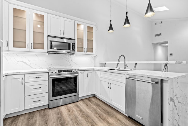 9676 Boca Gardens Pkwy Unit C, Boca Raton, FL 33496 - kitchen featuring appliances with stainless steel finishes, a peninsula, crown molding, a skylight, and light wood-style flooring