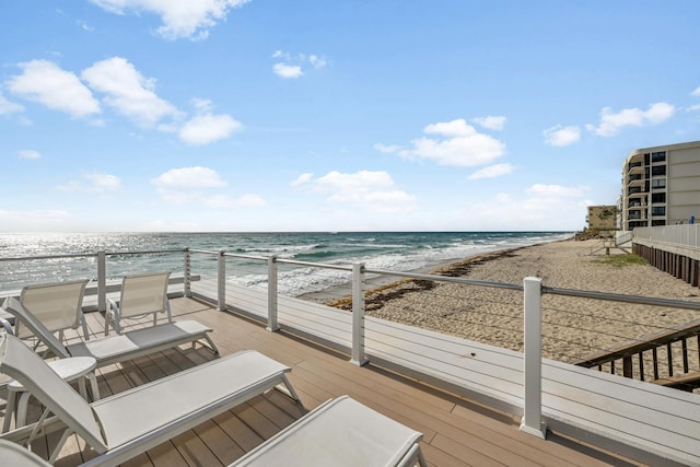 wooden terrace with a water view and a view of the beach
