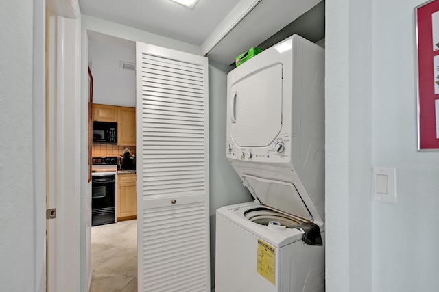 laundry room with laundry area, light tile patterned floors, and stacked washer and clothes dryer