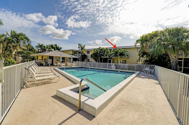 community pool featuring a jacuzzi, a patio, and fence