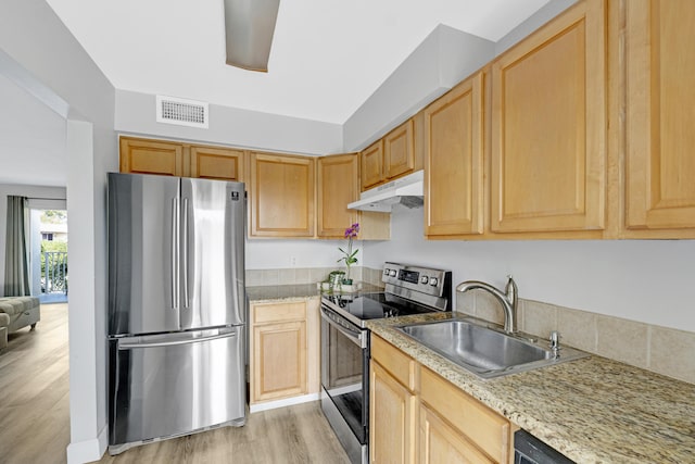 kitchen with appliances with stainless steel finishes, under cabinet range hood, a sink, light wood-style flooring, and light brown cabinetry