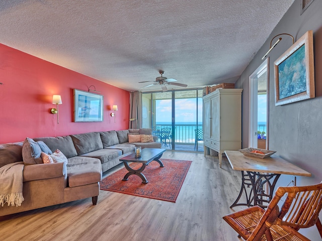 living area with ceiling fan, floor to ceiling windows, a textured ceiling, and wood finished floors