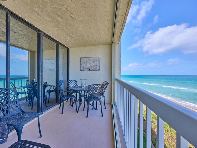 balcony with a beach view, a water view, and a baseboard heating unit