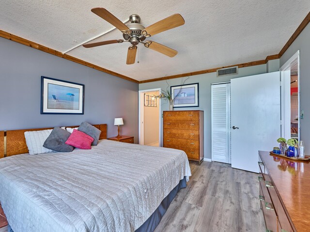 bedroom featuring visible vents, a textured ceiling, crown molding, and wood finished floors