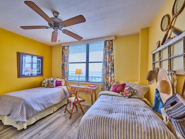 bedroom featuring a textured ceiling, a ceiling fan, and wood finished floors