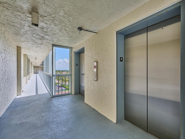 view of exterior entry featuring stucco siding, elevator, and a balcony