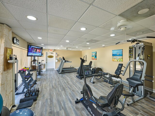 exercise room featuring recessed lighting, baseboards, a drop ceiling, and wood finished floors