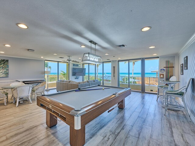 recreation room with visible vents, a textured ceiling, crown molding, and light wood-type flooring