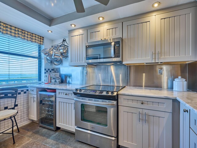 kitchen with ceiling fan, appliances with stainless steel finishes, light stone counters, beverage cooler, and recessed lighting