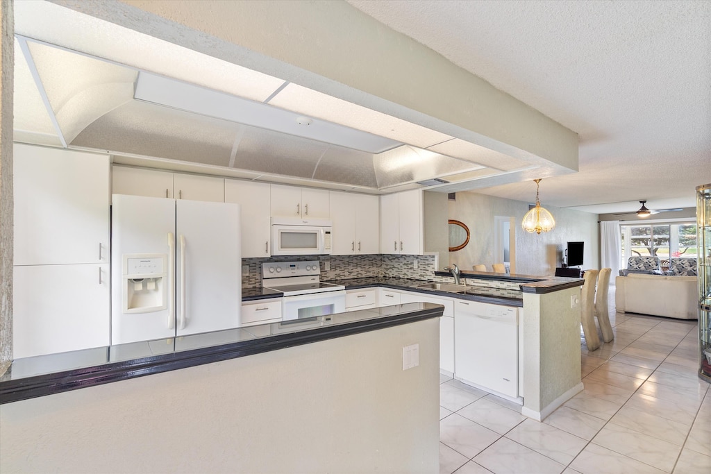 1904 Bermuda Cir Unit A1, Coconut Creek, FL 33066 - kitchen featuring decorative backsplash, a peninsula, dark countertops, white appliances, and white cabinets