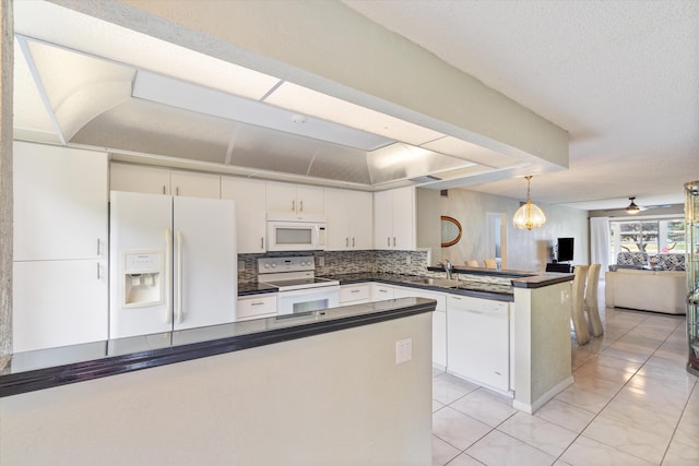 kitchen featuring decorative backsplash, a peninsula, dark countertops, white appliances, and white cabinets