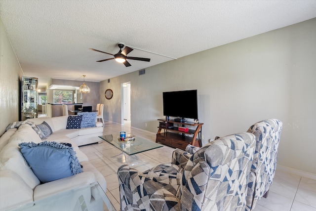 living area featuring visible vents, a textured ceiling, ceiling fan with notable chandelier, and baseboards