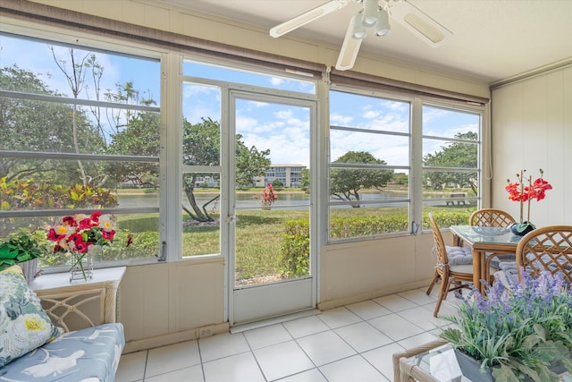 sunroom featuring a ceiling fan and a water view