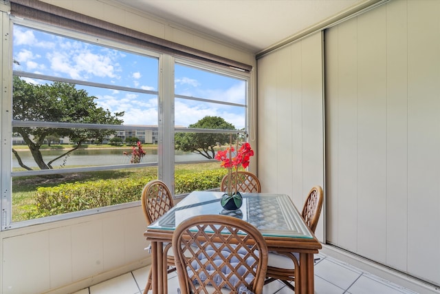 sunroom with plenty of natural light, outdoor dining space, and a water view