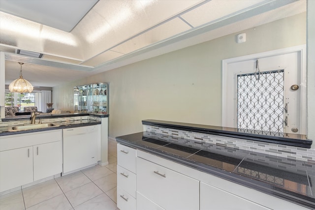 kitchen with an inviting chandelier, dark countertops, tasteful backsplash, a sink, and dishwasher